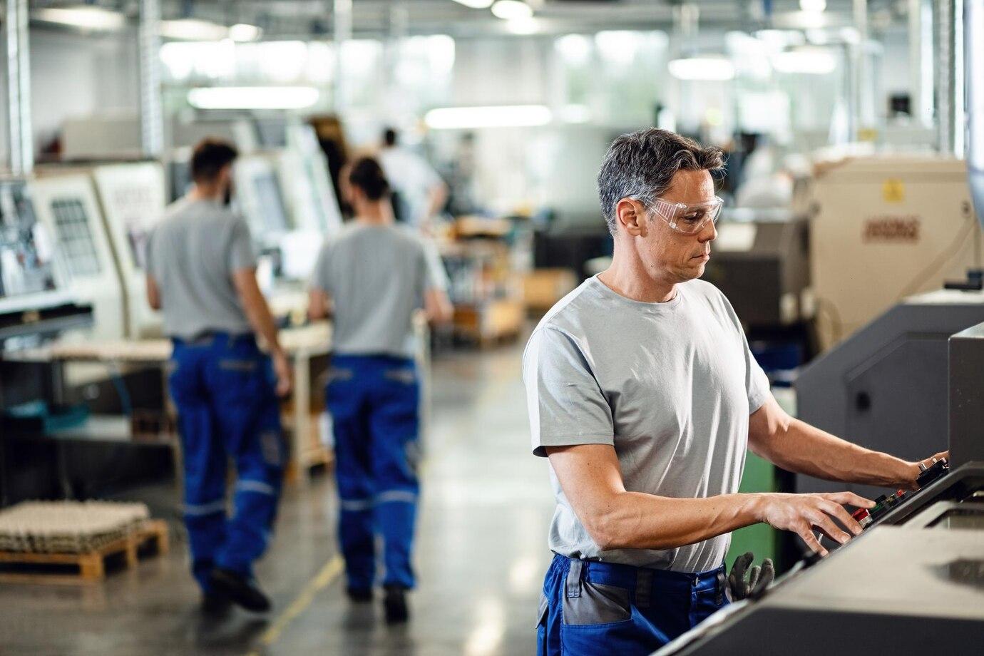 mid adult worker operating a cnc machine while working in industrial facility 637285 4166